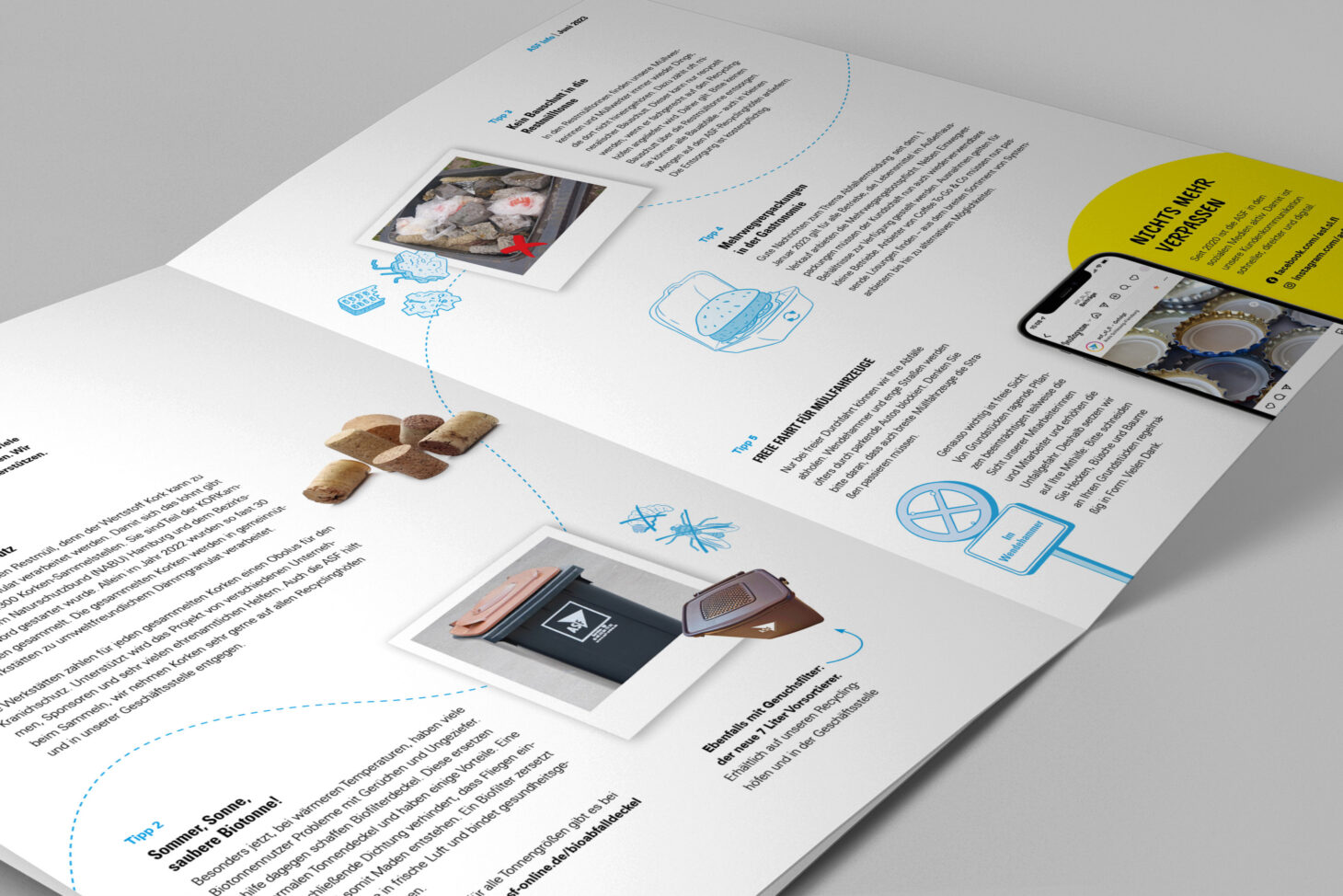 Die Zeitschrift ASF Info liegt aufgeschlagen auf einer Oberfläche, es sind Biotonnen, blaue Illustrationen und ein Smartphone zu sehen