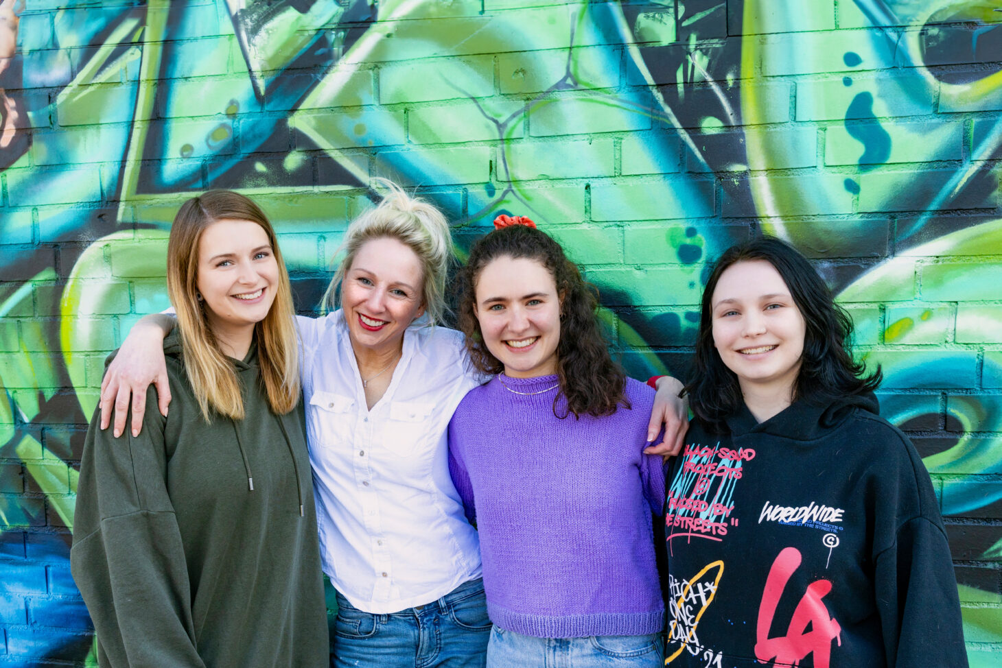 Vier Frauen stehen vor einer Graffiti-Wand